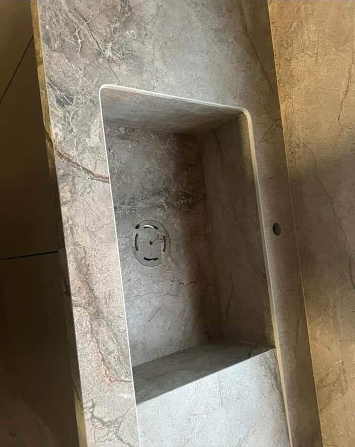 כיור אינטגרלי חצוב במשטח שיש בגוון אבן טבעית חומה-אפורה