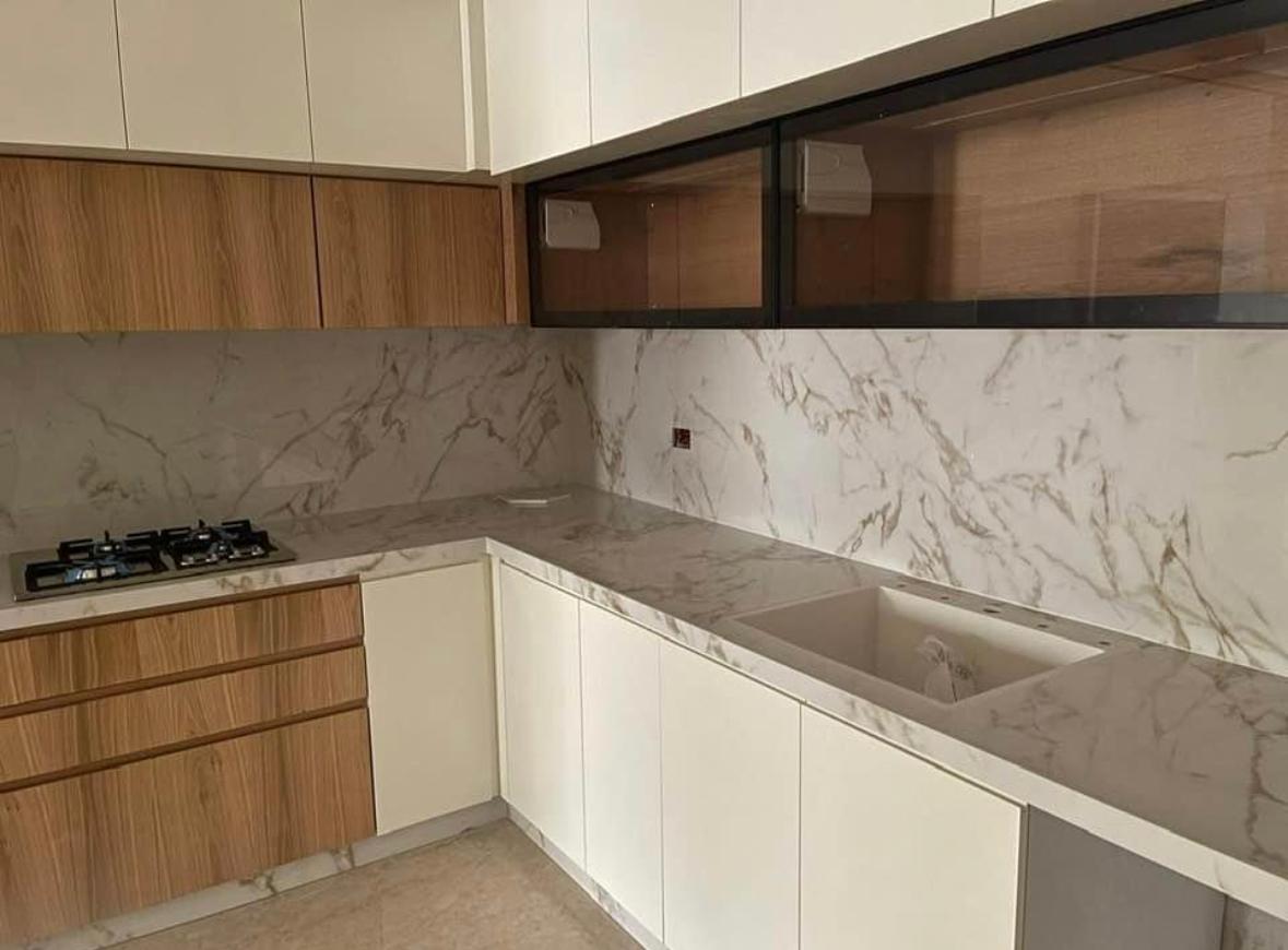 מטבח לבן עם ארונות עץ, משטח וחיפוי קיר בגרניט פורצלן דמוי שיש לבן
